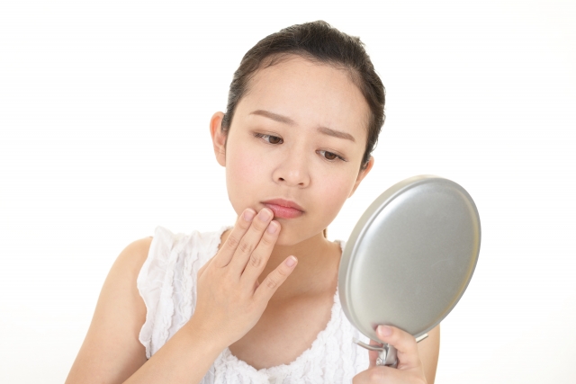 唇の乾燥を鏡で確認する女性