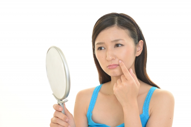 口元のシミを鏡で確認する女性