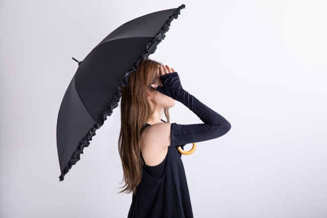 日傘やアームカバーで日焼け対策をする女性